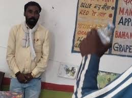 Middle-aged teacher with beard sitting in a rural classroom, caught smoking during school hours – Guna, Madhya Pradesh.