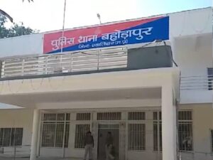 Fraudster swapping ATM card in Gwalior while posing as helper, with victim visible at machine - surveillance still image