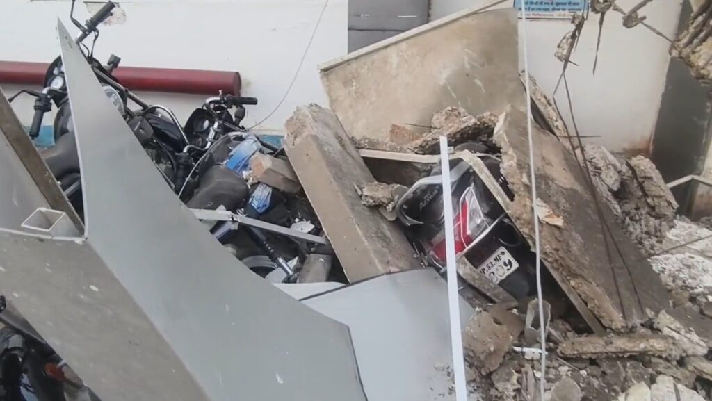 Collapsed main gate of Sidhi District Hospital with nearby damaged vehicles and no casualties reported.